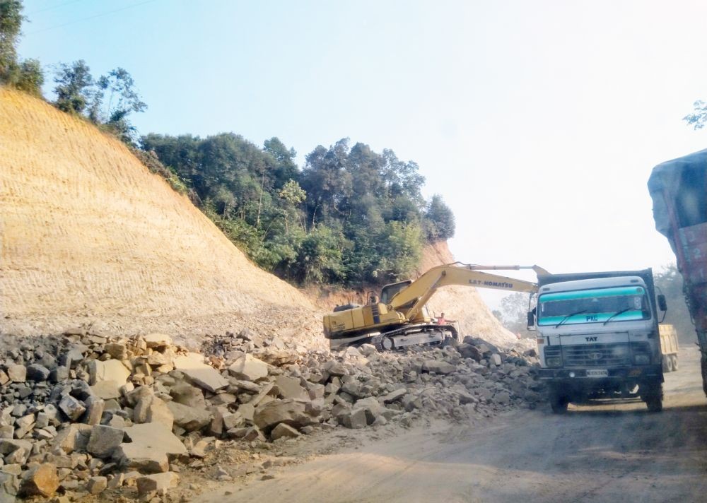 Vehicles drive past an excavator engaged in the construction work along a stretch of NH-29 between Dimapur and Kohima. As per the Ministry Of Road Transport and Highways (MoRTH), works for the four-laning of NH-29 from Dimapur to Kohima, are going “on schedule.” (Morung File Photo)